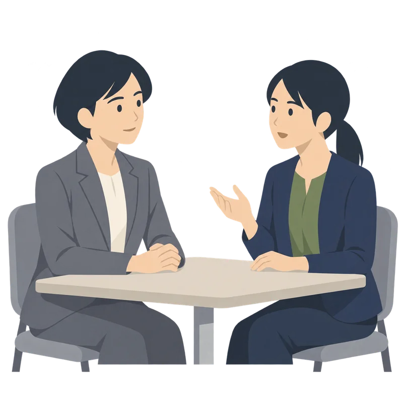 机をはさんで、上司と部下（どちらも女性）が落ち着いて話し合っている面談の場面